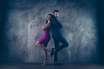Poster - Full size body portrait of attractive couple with crossed arms looking at camera, charming slim lady in purple tight dress gentlemen in tux  standing back to back over grey wall