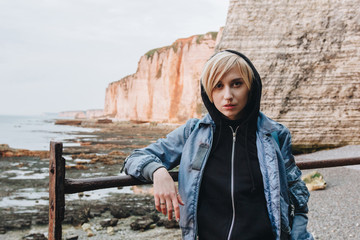 Wall Mural - beautiful young woman standing in front of rocky cliffs on seashore