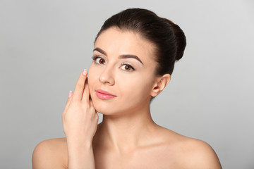 Beautiful young woman with silky skin after spa treatment on light background