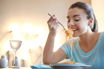 Young woman eating tasty pasta in cafe