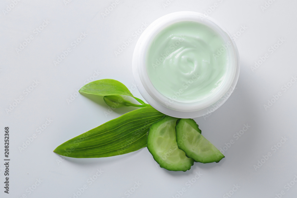 Body cream and cucumber slices on white background