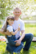 © ALEXEY - Father hugs his little daughter. Dad and daughter are sitting together in a city park.