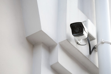 Modern CCTV camera on wall of building outdoors