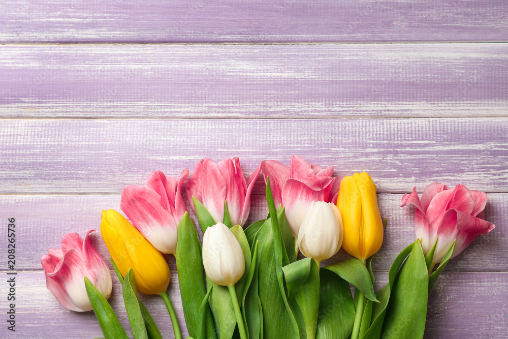 Beautiful fresh tulips on color wooden background