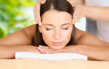 wellness, spa and beauty concept - close up of beautiful woman having face massage over green natural background