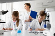 © Syda Productions - education, science and children concept - teacher and students studying chemistry at school laboratory and writing to workbooks