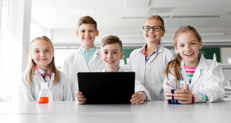 Wall Mural - education, science and technology concept - happy kids with tablet pc computer studying chemistry at