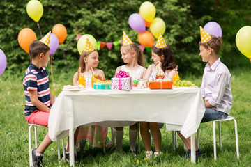 Poster - holidays, childhood and celebration concept - happy kids sitting at table on birthday party at summer garden