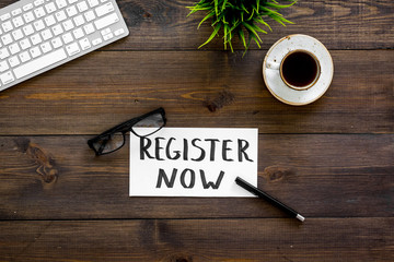 Poster - Membership concept. Template for registration. Register now hand lettering iconon word desk with glasses, coffee, plant on dark wooden background top view space for text