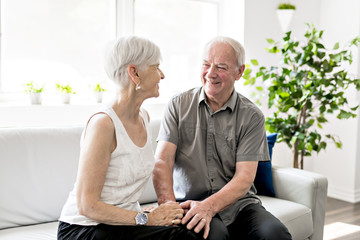 Affectionate attractive elderly couple sitting together on a couch