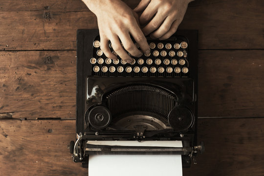 Young man's hands typing on an antique vintage typewriter