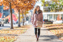 Young Happy Woman Walking On Sidewalk Street In Washington DC, USA United States Legs In Alley Of Golden Orange Yellow Foliage Autumn Fall Trees On Road During Sunny Day