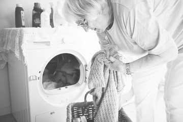 Wall Mural - Elderly woman doing laundry at home