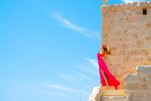 Beautiful Girl In A Long Pink Dress Standing On The Edge Of The White Cliffs By The Church Of St Mary Magdalen On The Island Of Malta