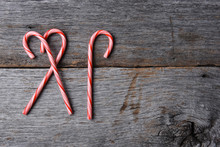 High Angle Shot Of Three Holiday Candy Canes On A Rustic Wood Table
