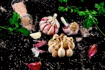 Food background with garlic, parsley and spilled pink salt.