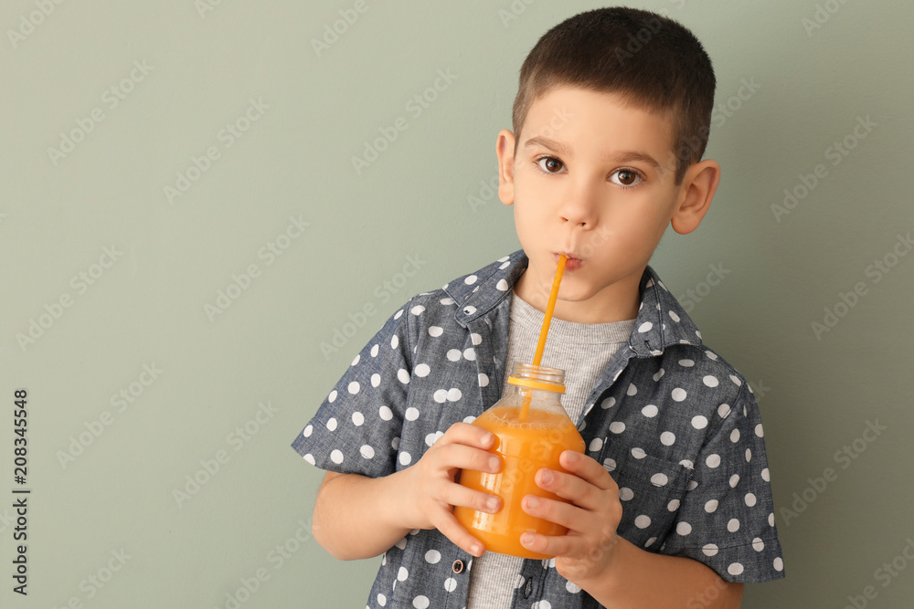 Funny little boy drinking citrus juice on color background