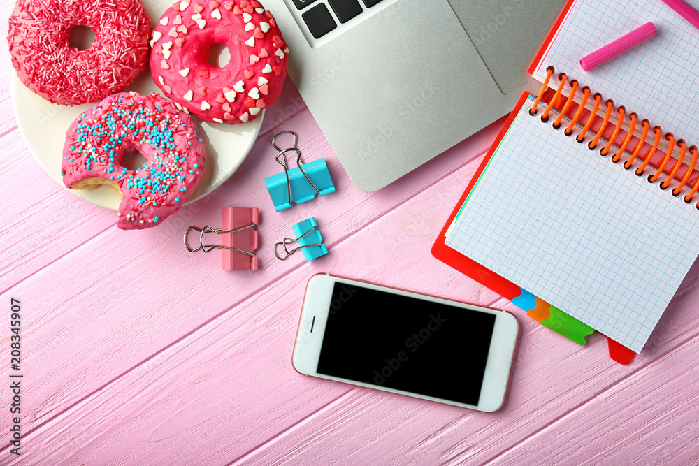 Laptop, smartphone, doughnuts and stationery on table, flat lay. Workplace composition