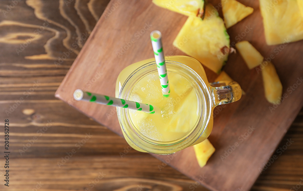 Mason jar with tasty fresh pineapple juice on wooden table