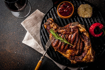 Wall Mural - Fresh grilled meat beef steak with with red wine, herbs and spices. Top view copy space dark rusty background