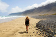 Girl is watching the suggestive landscape of Caleta Famara, Lanzarote, Canary Islands
