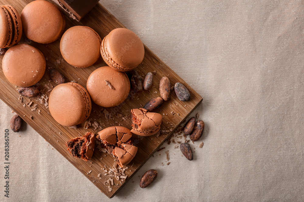 Composition with chocolate macarons on wooden board, top view