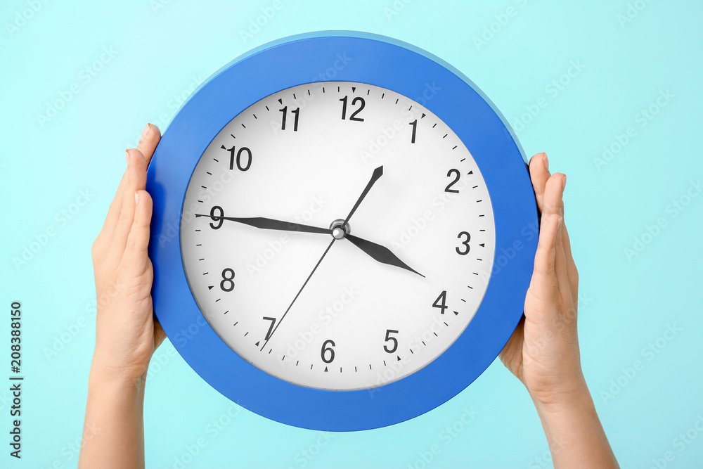 Woman holding clock on color background. Time management concept