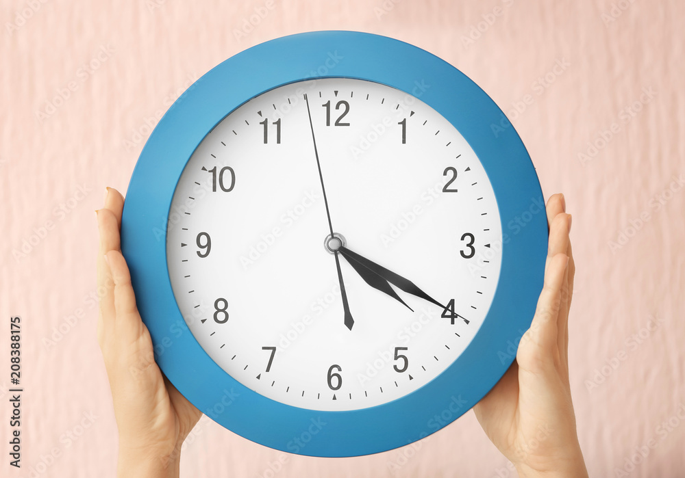 Woman holding clock on color background. Time management concept