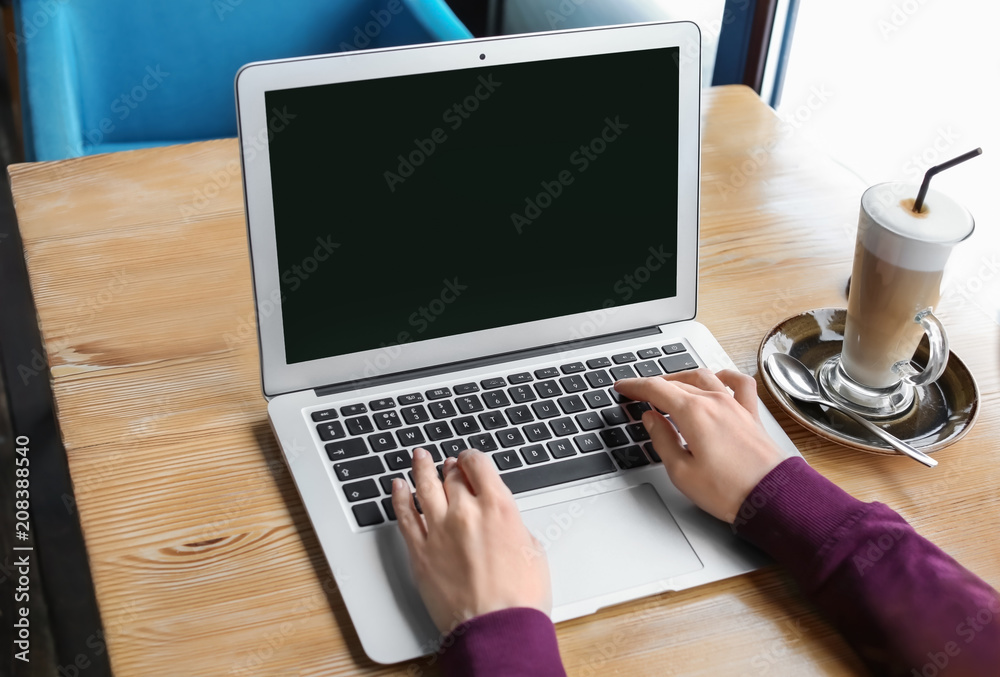 Young woman using laptop at table, indoors