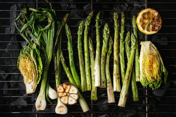 Grilled vegetables green asparagus, garlic, lemon, spring onion, salad on bbq grill rack over charcoal. Top view, space.