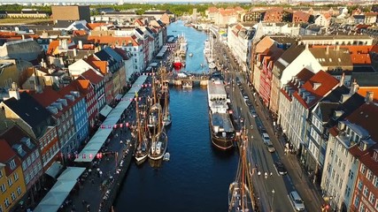 Wall Mural - Busy Copenhagen, Denmark sunset street. Walking, cycling, car traffic. Nyhavn New Harbour canal. Aerial Video footage view from the top. street walking people. camera rotates from the sky downwards