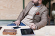 © Maskot - Midsection of businessman with digital tablet and smart phone sitting at table in creative office