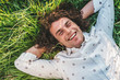 © iuricazac - People, lifestyle. Outdoor close up portrait of happy handsome young male smiling with white toothy smile lying on the green grass in the park, looking at the camera with copy space for advertising.