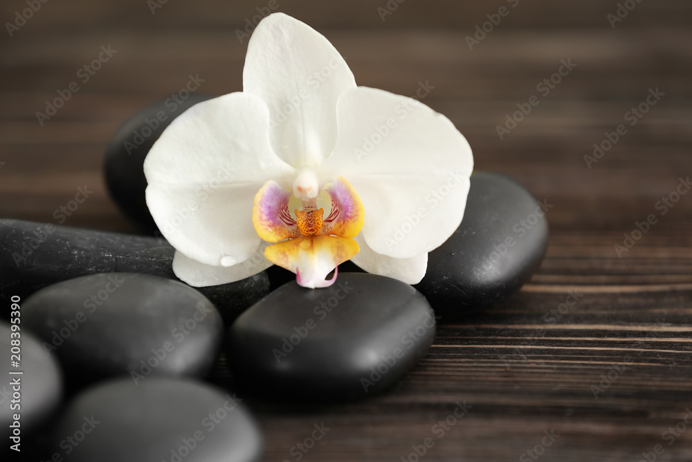 Spa stones with beautiful orchid flower on wooden background