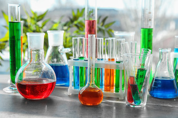 Chemical glassware with colorful samples on table