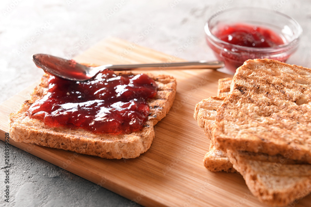 Toasted bread with jam on wooden board