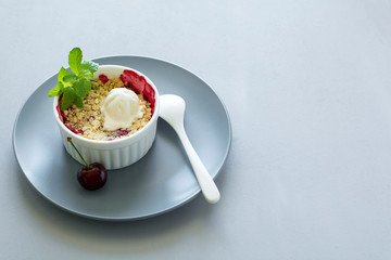 Wall Mural - Cherry crumble with oatmeal and ice cream in bowl on grey wooden desk. Summer healthy food