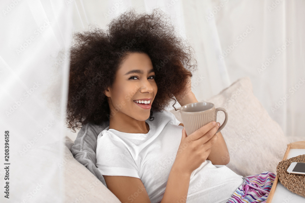 Beautiful African-American woman drinking tea at home