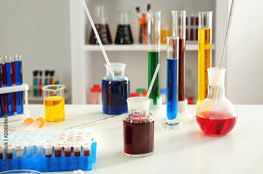Chemical glassware with colorful liquids on table