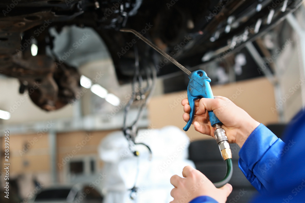 Male mechanic lubricating car in service center