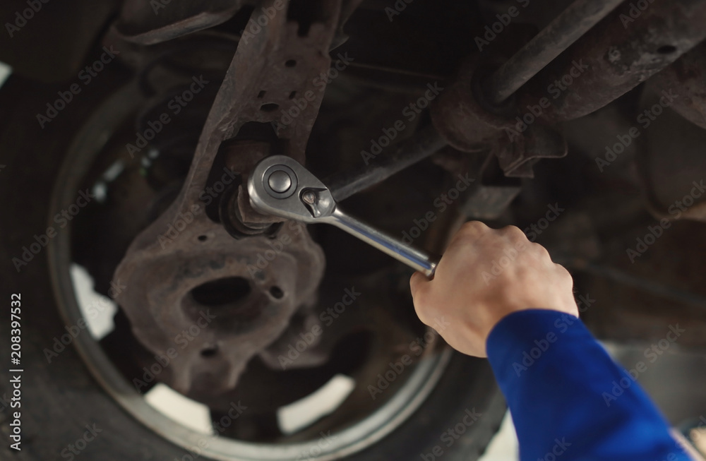 Male mechanic fixing car in service center