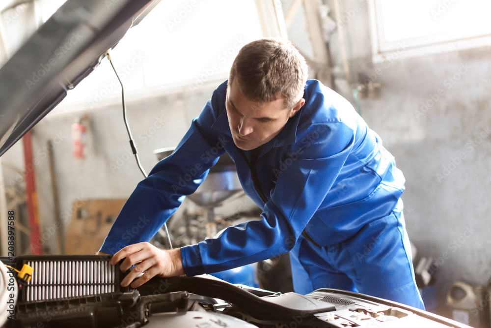 Male mechanic examining car in service center