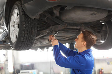 Male mechanic fixing car in service center