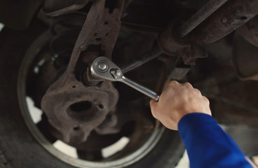 Male mechanic fixing car in service center