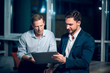 © Svyatoslav Lypynskyy - Two coworkers staying up late working. Business colleagues viewing presentation via touchscreen tablet sitting in modern office late at night.