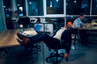 © Svyatoslav Lypynskyy - Guy lying in his chair asleep in office. Three businessmen working in office late at night one of them sitting in his chair with his feet up on table snoozing.