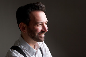 Wall Mural - Side of handsome man with beard smiling against gray backgorund