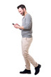 Full length side of man walking with mobile phone