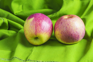 Two red apples on green napkin close up