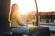 © terovesalainen - Happy woman in sunset waiting for train. Lady sitting with baggage, luggage and suitcase in platform at station. Travel and lifestyle concept.